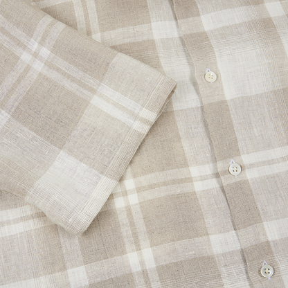A close-up of the Maurizio Baldassari Light Brown Linen Check Short Sleeve Shirt shows its beige and white checks, short sleeve detail, three white buttons, and lightly textured fabric with intersecting lines. , available at Richard Gelding Mayfair