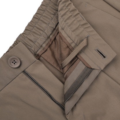Close-up of Herno's dark beige nylon stretch drawstring trousers, featuring an open zipper, button closure, and elastic waistband for a blend of casual comfort and modern style with a slim fit.