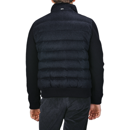 Man wearing a navy blue cashmere silk bomber jacket from Herno, photographed from the back with gray pants against a plain background.
