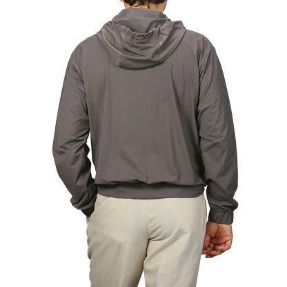 A person wears a Herno Taupe Beige Nylon Jersey Hood Jacket paired with light pants, facing away from the camera against a plain background.