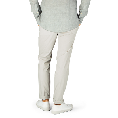 Man in casual attire standing with hands in pockets, wearing Hiltl cream beige cotton nylon slim chinos.