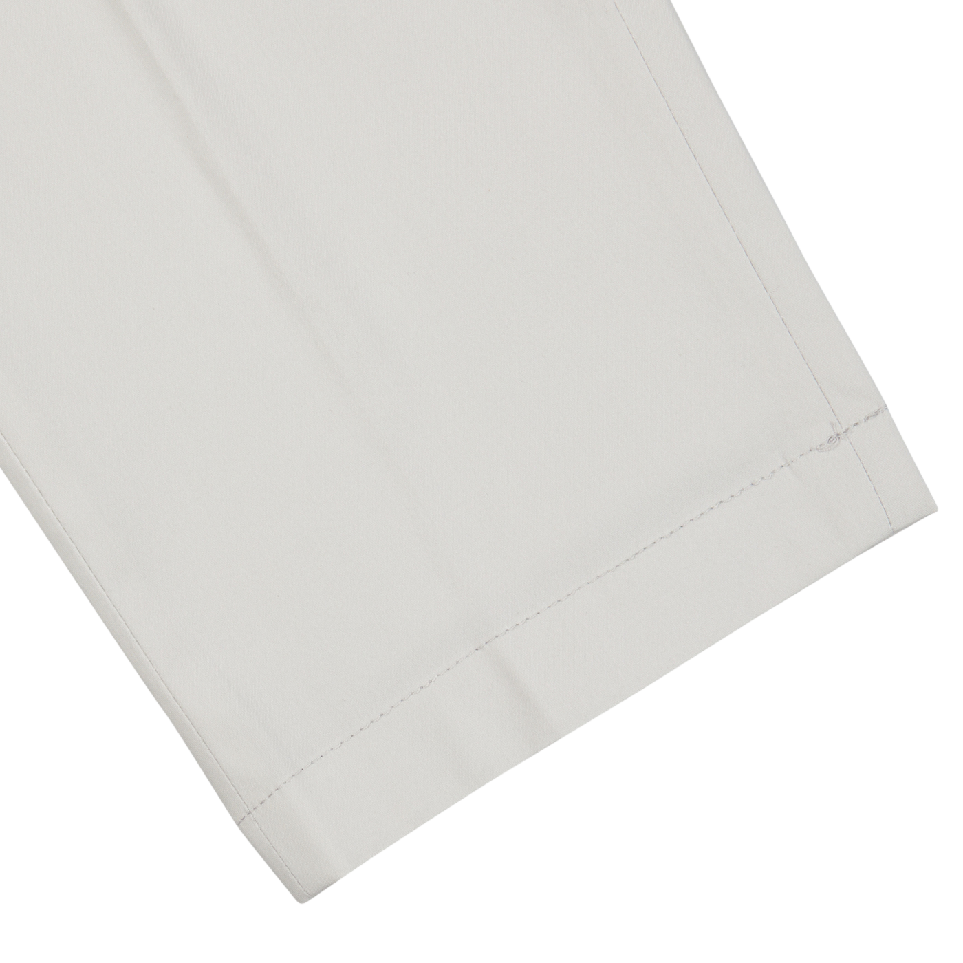 A close-up of neatly folded Hiltl cream beige cotton nylon slim chinos with visible stitching.