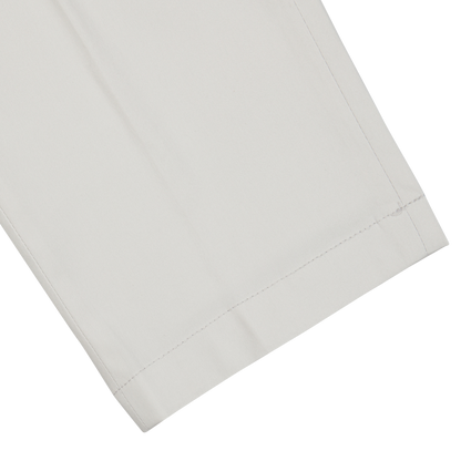 A close-up of neatly folded Hiltl cream beige cotton nylon slim chinos with visible stitching.