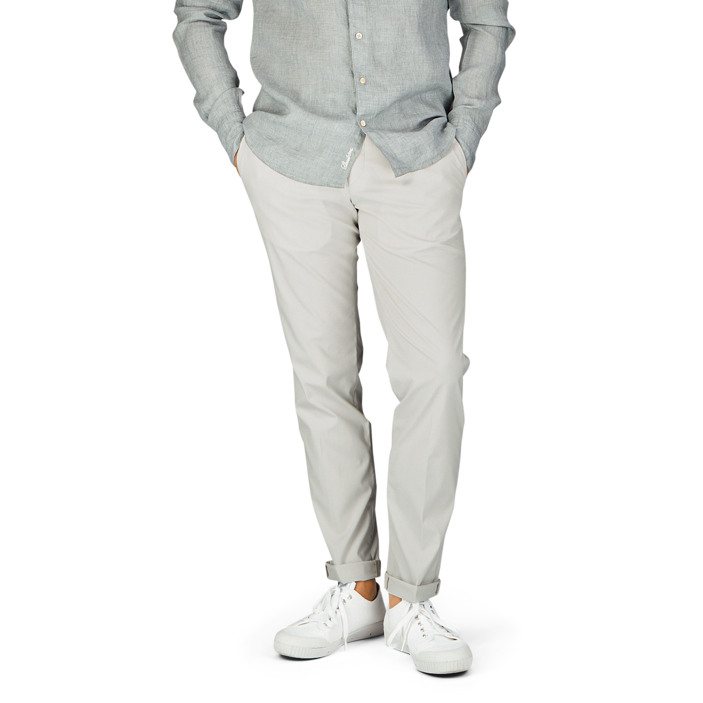 Casual attire – man in a light grey shirt, Hiltl cream beige cotton nylon slim chinos, and white sneakers.