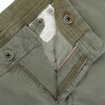 Close-up of the Green Washed Cotton Gabardine Slim Chinos by Hiltl, showcasing a partially unzipped fly, two buttons, and a visible clothing tag.
