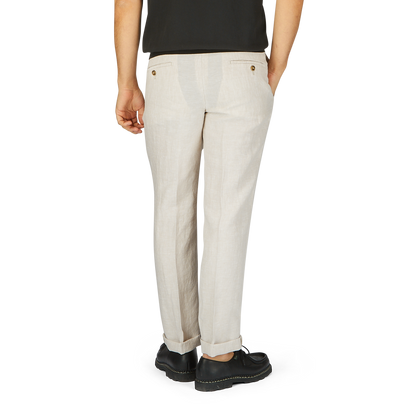 Back view of a person wearing Light Beige Washed Linen Regular Fit Chinos by Hiltl and black shoes, standing against a gray background.