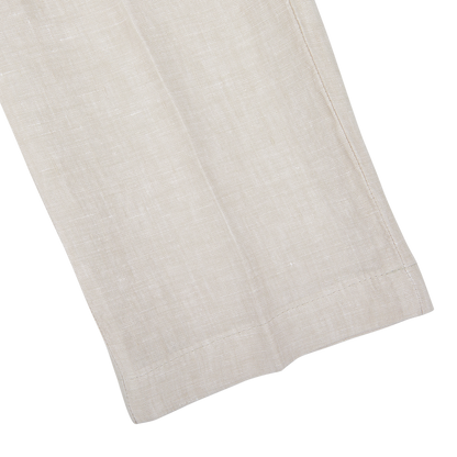 Close-up of a Hiltl light beige washed linen regular fit chinos with a subtle texture and visible weave, laid flat on a white background.