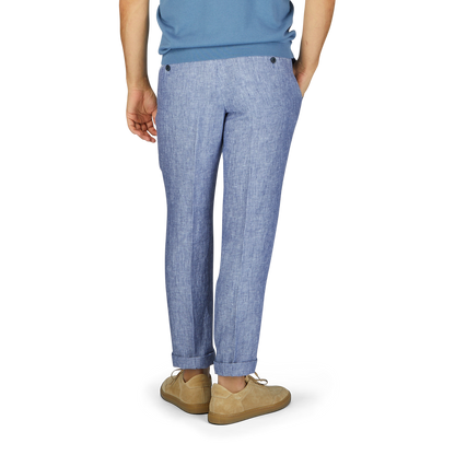 Man wearing Hiltl light blue washed linen regular fit chinos, and beige shoes, standing with his left side facing the camera, isolated on a white background.