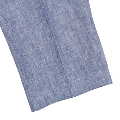 Close-up of a folded light blue melange linen fabric with a visible texture, isolated on a white background.