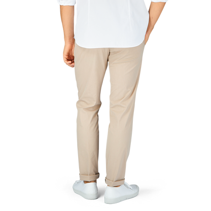Man standing in a white t-shirt, Hiltl sand beige cotton nylon slim chinos, and white sneakers.