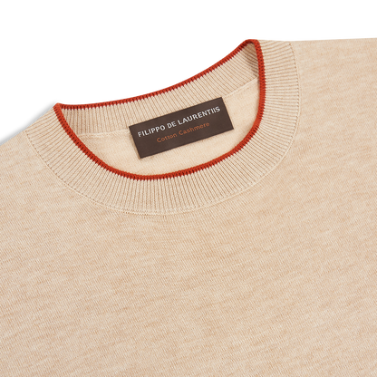 The Filippo de Laurentiis Beige/Terracotta Cotton Cashmere Crew Neck Sweater features a round neckline with thin red trim and a brown inner label, offering soft, fine knitwear perfect for comfort lovers. , available at Richard Gelding Mayfair