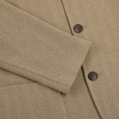 Close-up of the Gran Sasso Beige Herringbone Cotton Blend Jacket, featuring its textured fabric and tailored details. The sleeve with two dark brown buttons rests over the front, highlighting this timeless design. , available at Richard Gelding Mayfair