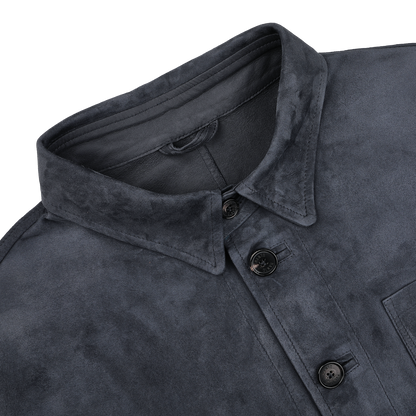 Close-up of the Manto Denim Blue Suede Unlined Jacket featuring a collared design with four black buttons and a visible chest pocket.