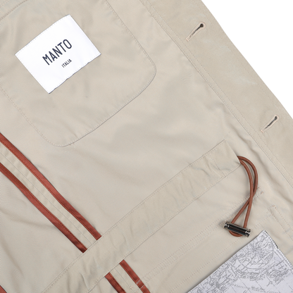 This Khaki Beige Ultrafine Microfibre Safari Jacket by Manto features a leather-trimmed interior, a MANTO label, a metal hook strap, and a soft map pattern. Its slim fit ensures both style and comfort.
