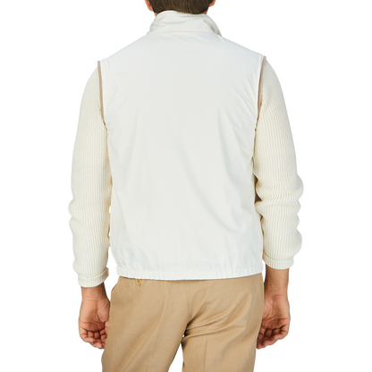 The man is wearing a white Beige Reversible Loro Piana Cashpima Gilet and tan pants by Manto.