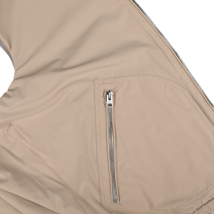 Close-up of the Manto Grey Beige Cashmere Nylon Reversible Gilet showcasing a zippered pocket with a metal zipper and a white pull tag. The gilet's fabric appears smooth and slightly shiny.