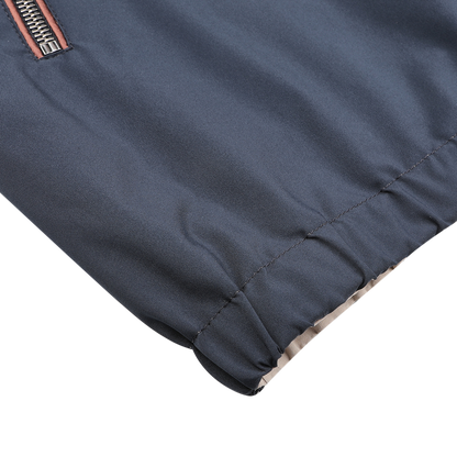 A close-up of the Navy Beige Reversible Nylon Blouson by Manto showcases its gray, water-resistant nylon fabric with a zipper and elastic hem for a sleek, slim fit look.