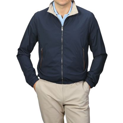 A person is wearing the Manto Navy Beige Reversible Nylon Blouson, featuring a beige collar, and matching beige pants. The slim-fit, water-resistant jacket is zipped up with hands in the pockets.