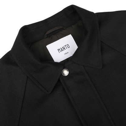 Close-up of the **Navy Blue Cashmere Car Coat** by **Manto**, featuring a pointed collar and a single front button. The label inside reads "Manto Italy." The luxurious cashmere outer exudes sophistication.