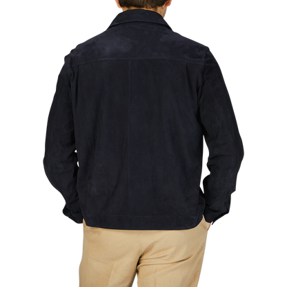 The back view of a man wearing a Manto Navy Blue Suede Leather Overshirt and tan pants.
