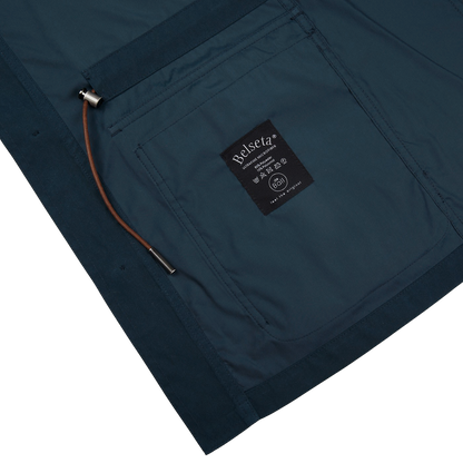 The water-resistant pocket of a Navy Blue Ultrafine Microfiber Safari Jacket by Manto with a logo on it.