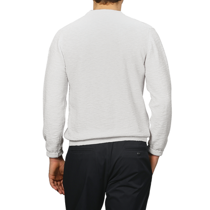 A person in a Cream Summer Mouline Crew Neck Sweater by Maurizio Baldassari and dark pants, viewed from the back, stands against a gray background.