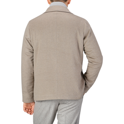 A person is shown from the back wearing a beige cashmere half padded chore coat by Maurizio Baldassari and grey pants against a plain background.