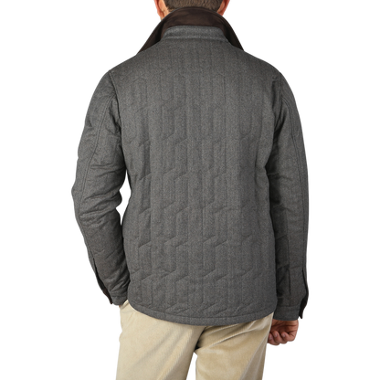 A person is standing with their back facing the camera, wearing a Taupe Beige Herringbone Quilted Virgin Wool Overshirt by Maurizio Baldassari and beige pants against a plain background.