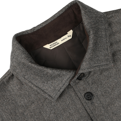 Close-up of a taupe beige herringbone quilted virgin wool overshirt collar with black buttons, showcasing a beige label inside that reads "Maurizio Baldassari made in Italy," and hinting at its subtle Thermore padding for added warmth.