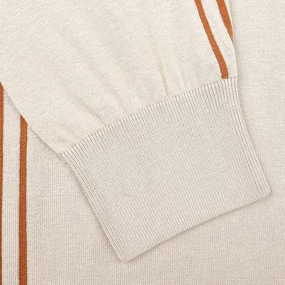 Close-up of a beige sleeve from the Maurizio Baldassari Silk Cotton Full Zip Tennis Polo Shirt, boasting ribbed cuffs and orange-brown vertical stripes on a textured fabric.