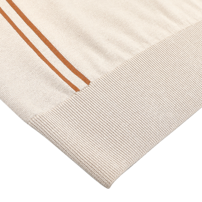 A close-up reveals the ribbed cuff of a Beige Silk Cotton Full Zip Tennis Polo Shirt by Maurizio Baldassari, crafted in an exquisite silk-cotton mix with two parallel brown stripes.
