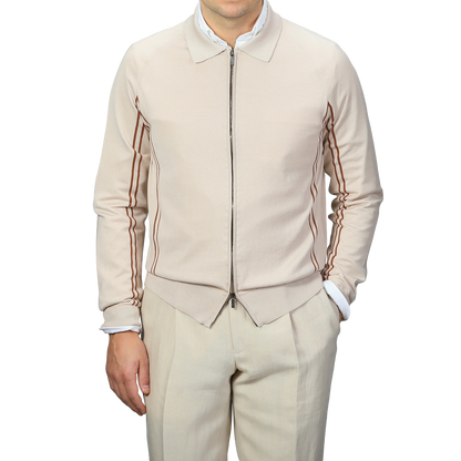 Dressed in a Maurizio Baldassari Beige Silk Cotton Full Zip Tennis Polo Shirt and beige pants, the person exudes Italian knitwear elegance against a gray background.