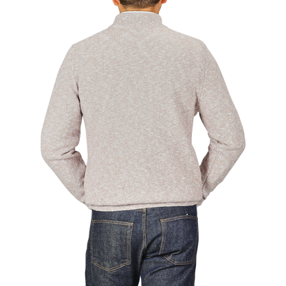 A person wearing a Maurizio Baldassari Beige Winter Wool Mouline 1/4 Zip Sweater and blue jeans stands facing away from the camera against a plain background.