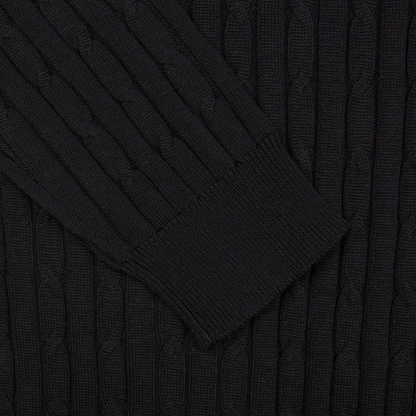 Close-up of a black Maurizio Baldassari Black Cotton Silk Cable-Knit 1/4 Zip Sweater with ribbed cuffs.