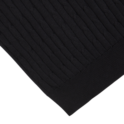 Close-up of a Maurizio Baldassari Black Cotton Silk Cable-Knit 1/4 Zip Sweater fabric with a ribbed and cable pattern, on a white background.