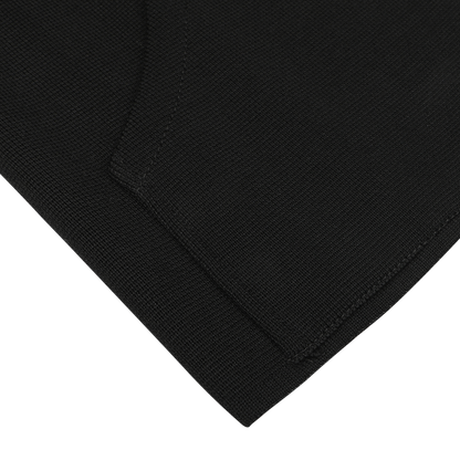 Close-up of the Black Milano Stitch Wool Zip Gilet by Maurizio Baldassari, featuring a folded corner that showcases the Milano stitch and texture detail. Made from virgin wool, this piece highlights impeccable stitching on a white background.
