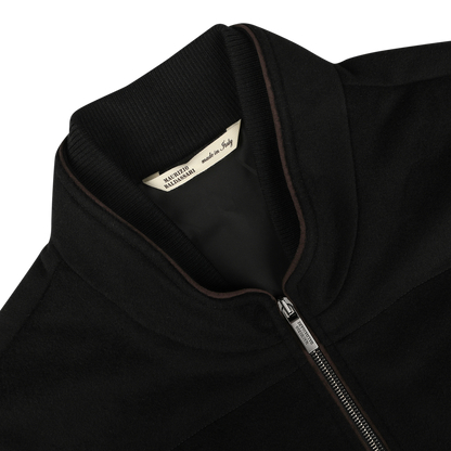 Close-up of a Black Water Repellent Cashmere Gilet with a ribbed collar. A tag inside the gilet reads "Made in Italy by Maurizio Baldassari.