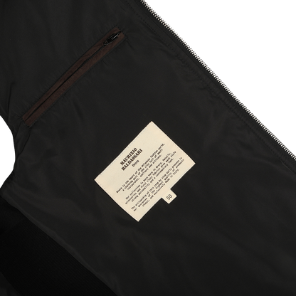 Close-up of the interior of the Maurizio Baldassari Black Water Repellent Cashmere Gilet, showcasing a cream label with text and a small pocket above it. The label provides maintenance or design details, hinting at the luxurious cashmere craftsmanship typical of the brand.