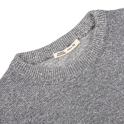 The Blue Melange Summer Mouline Crew Neck Sweater by Maurizio Baldassari is crafted from a luxurious cotton-viscose blend, featuring a visible woven texture enhanced by a subtle summer mouline knit, with a white label on the collar displaying text.