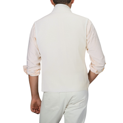 A man is shown from behind wearing a Maurizio Baldassari Cream Milano Stitch Wool Zip Gilet, a light-colored rolled-up sleeve shirt, and cream-colored pants.