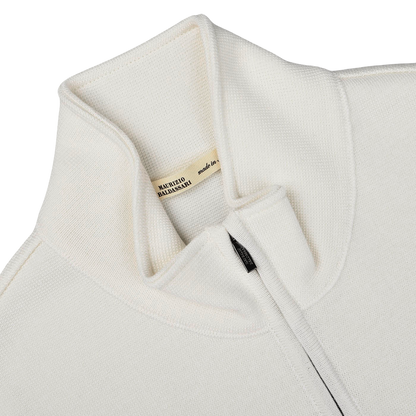 Close-up of the Cream Milano Stitch Wool Zip Gilet featuring a high collar and a zipped front, crafted with care. A beige label inside reads "MAURIZIO BALDASSARI made in Italy," reflecting its premium quality and design expertise.