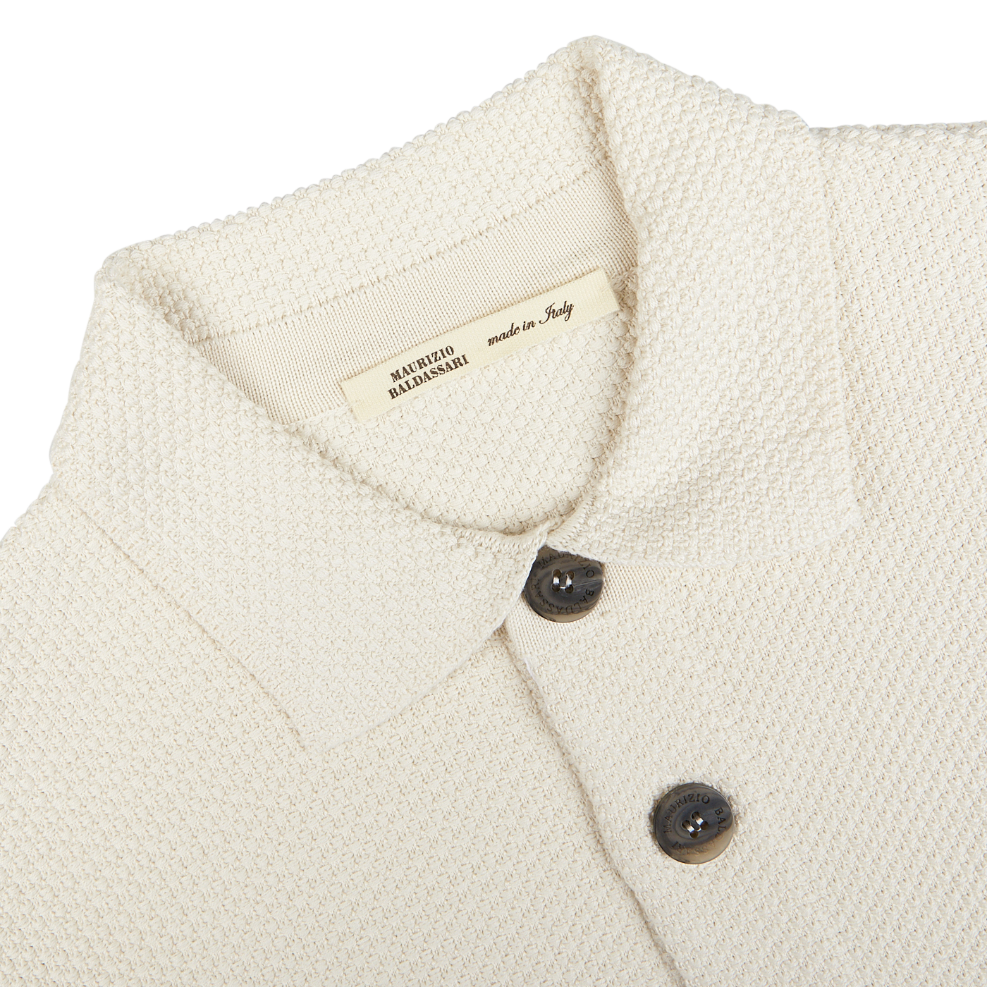 Close-up of a Cream Beige Silk Cotton Knitted Blouson collar and buttons with a label indicating "made in Italy" by Maurizio Baldassari.