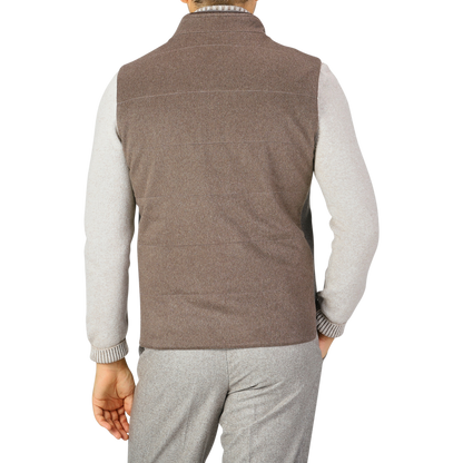 A person is seen from the back, wearing a Maurizio Baldassari Dark Taupe Water Repellent Cashmere Gilet over a light gray long-sleeve shirt and gray pants.