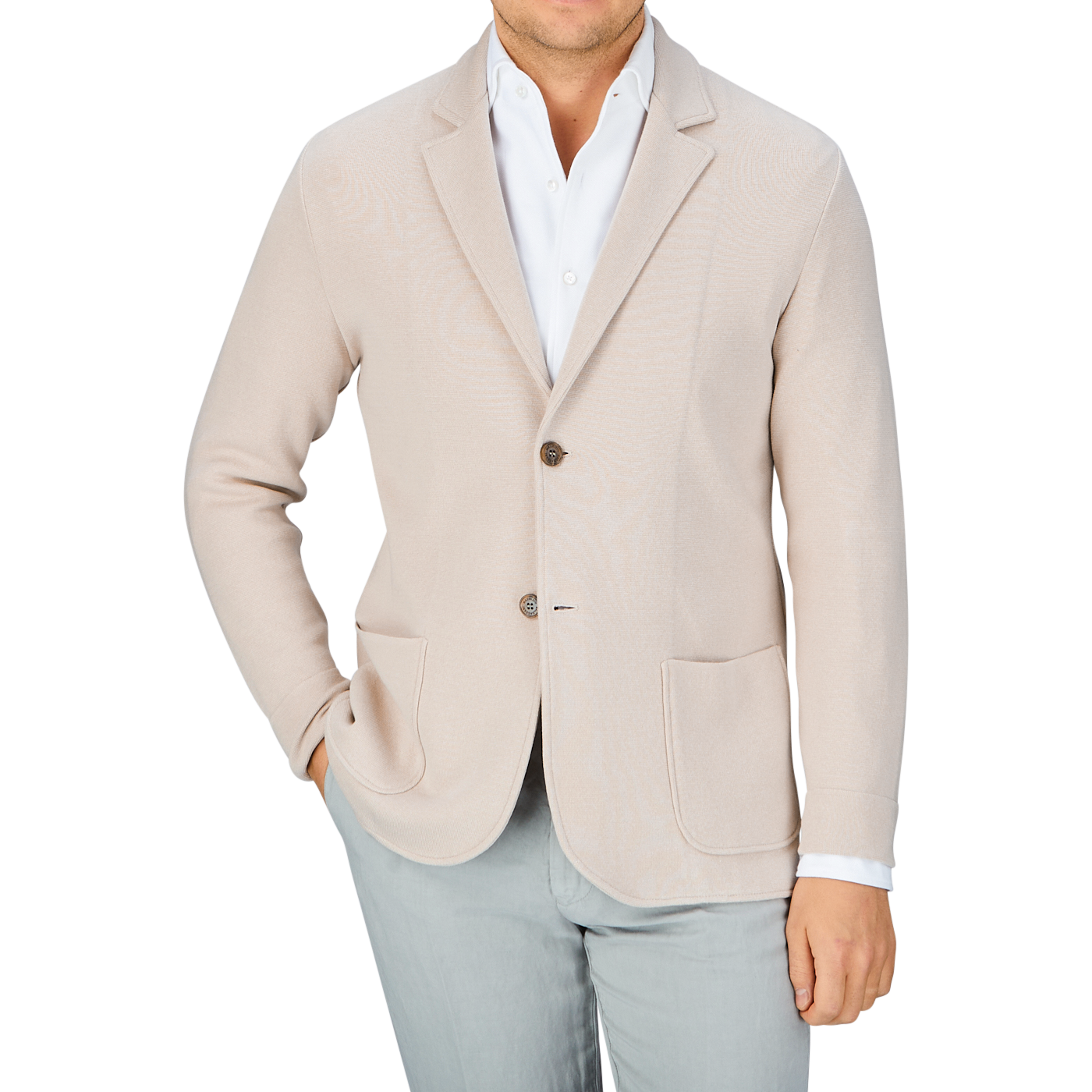 Man in a Maurizio Baldassari light beige silk cotton knitted Milano blazer and light grey pants with a white shirt unbuttoned at the collar, offering a casual substitute to formal wear.