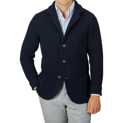 A person wearing a Maurizio Baldassari Navy Blue Zegna Baruffa Wool Brenta Jacket over a white and blue striped shirt and gray trousers, showcasing exceptional craftsmanship. The face is not visible.
