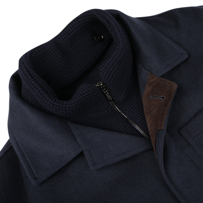 Close-up of the Navy Cashmere Half Padded Chore Coat by Maurizio Baldassari, featuring a high ribbed collar, a partially open zipper, and a brown suede accent near the lapel. The inclusion of Thermore technical down ensures optimal warmth and comfort.