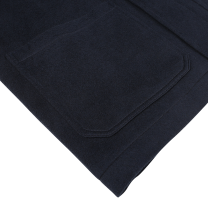 Close-up of a navy blue fabric with a pocket from the Maurizio Baldassari Navy Cashmere Half Padded Chore Coat, showcasing fine stitching and texture details, placed on a white background.