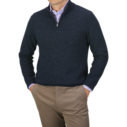 A person wearing a Maurizio Baldassari Navy Winter Wool Mouline 1/4 Zip Sweater over a light purple shirt, paired with light brown pants, stands with hands in pockets against a gray background.