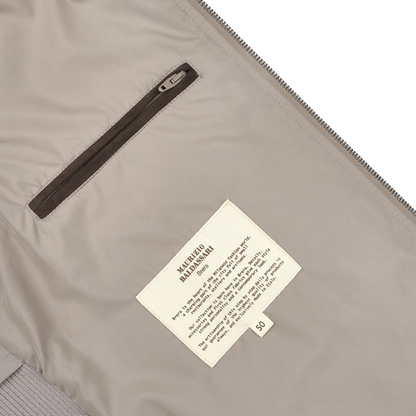 Inside the Maurizio Baldassari Pale Beige Nylon Thermore Travel Gilet, you’ll find a brown zippered pocket and a white care label. Made from technical nylon, this gilet offers durability and functionality.