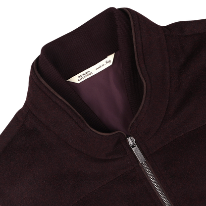 A close-up of a plum water-repellent cashmere gilet from Maurizio Baldassari, featuring a silver zipper and a label inside the collar that reads "Made in Italy." The fabric boasts 100% cashmere, offering luxurious comfort.